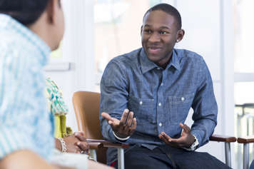 Teen sitting in a chair across from two adults and smiling at them