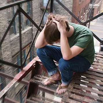 Teen boy sitting on steps with head in his hands