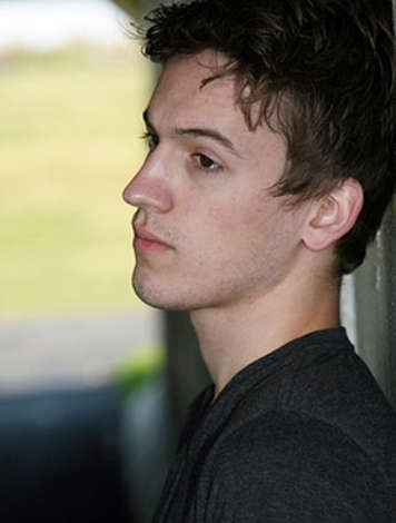 Teen boy resting head against a wall